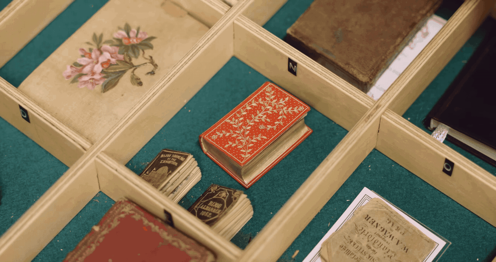 A gif of a hand reaching into a drawer full of tiny books and pulling one out