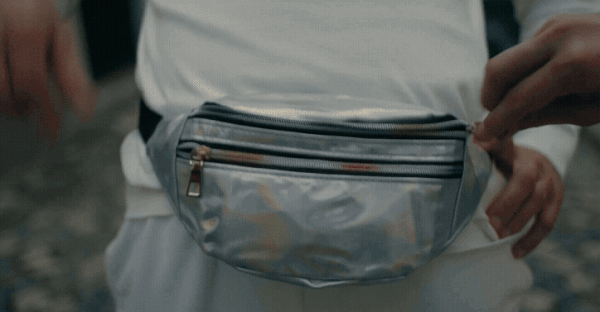 a gif from a Xinobi music video directed by Callner Brothers, showing two men with fanny packs on, and one reaches in one to grab a pink sticker that reads "muy bien"