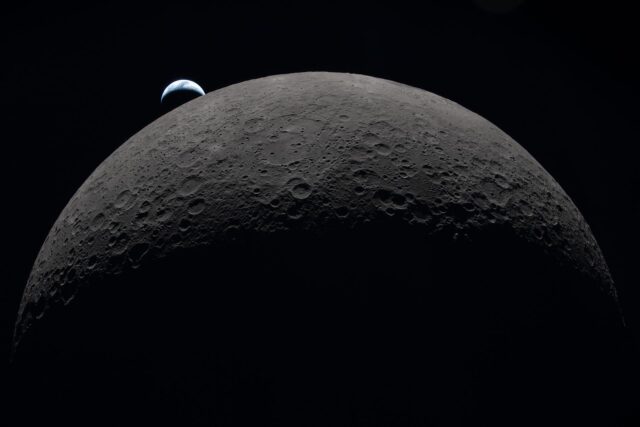 A photo taken during the Artemis II mission around the Moon huge in the foreground, with the Earth setting beyond