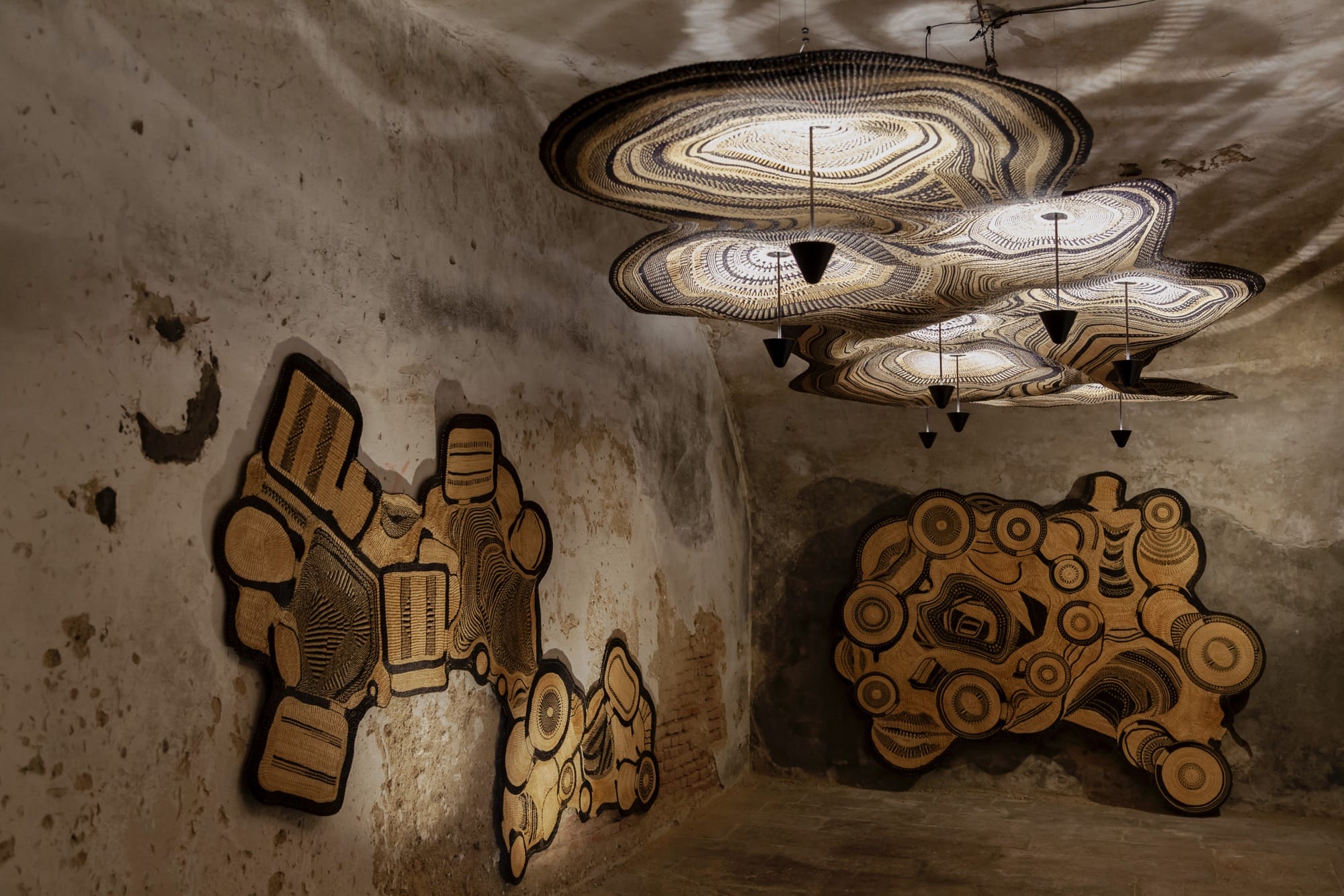 A detail of a sprawling light fixture produced by Ghanaian artisans in collaboration with PET Lamp with swirling, woven designs, with additional pieces installed around the room