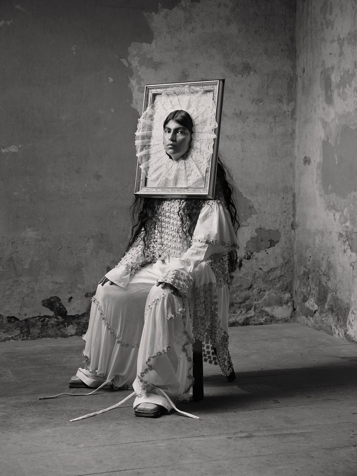 a black and white portrait by Pieter Henket of a person seated on a stool wearing a lace dress and a framed frilly lace piece on their face