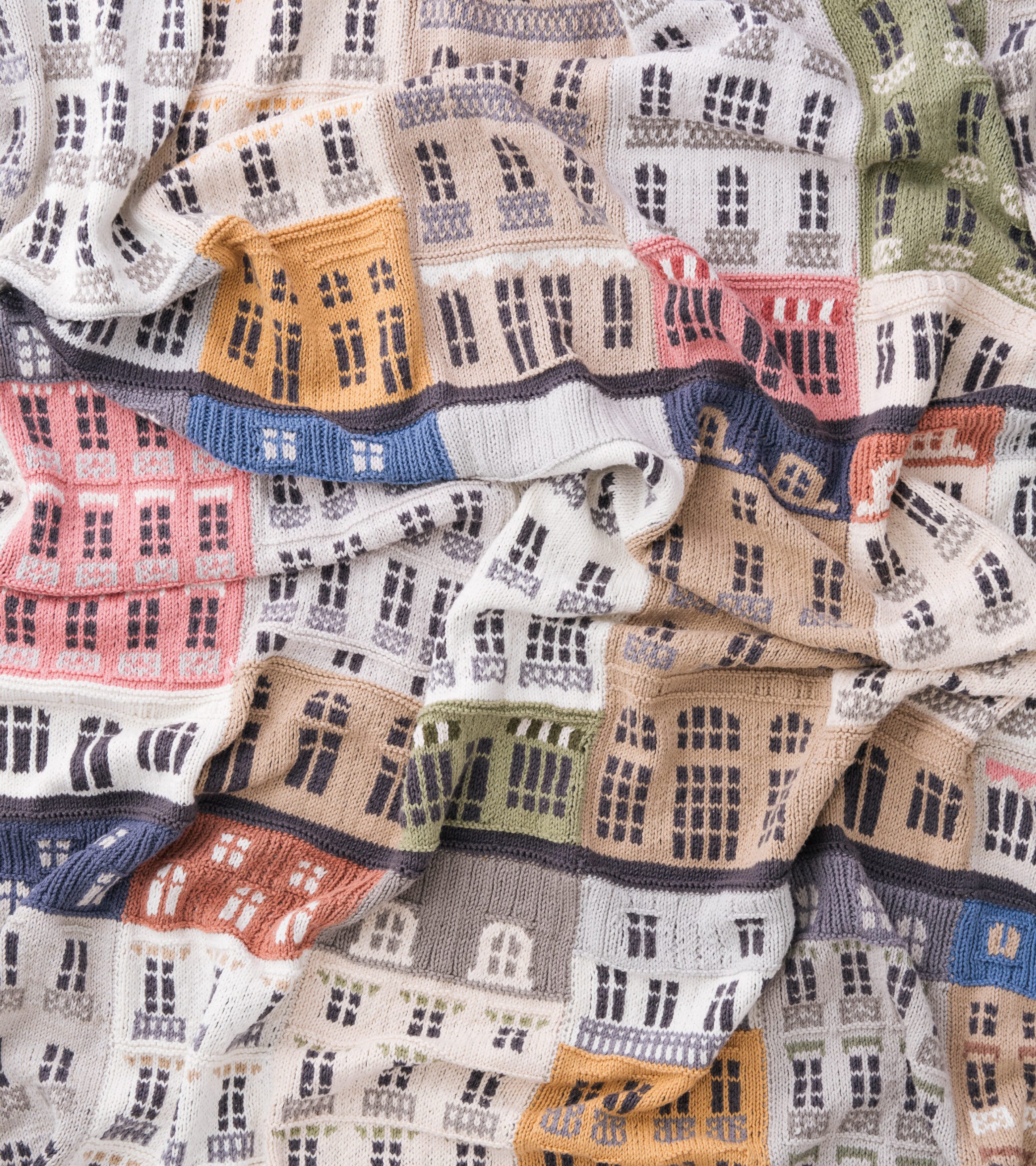 A knitted blanket with panels that resemble numerous building facades