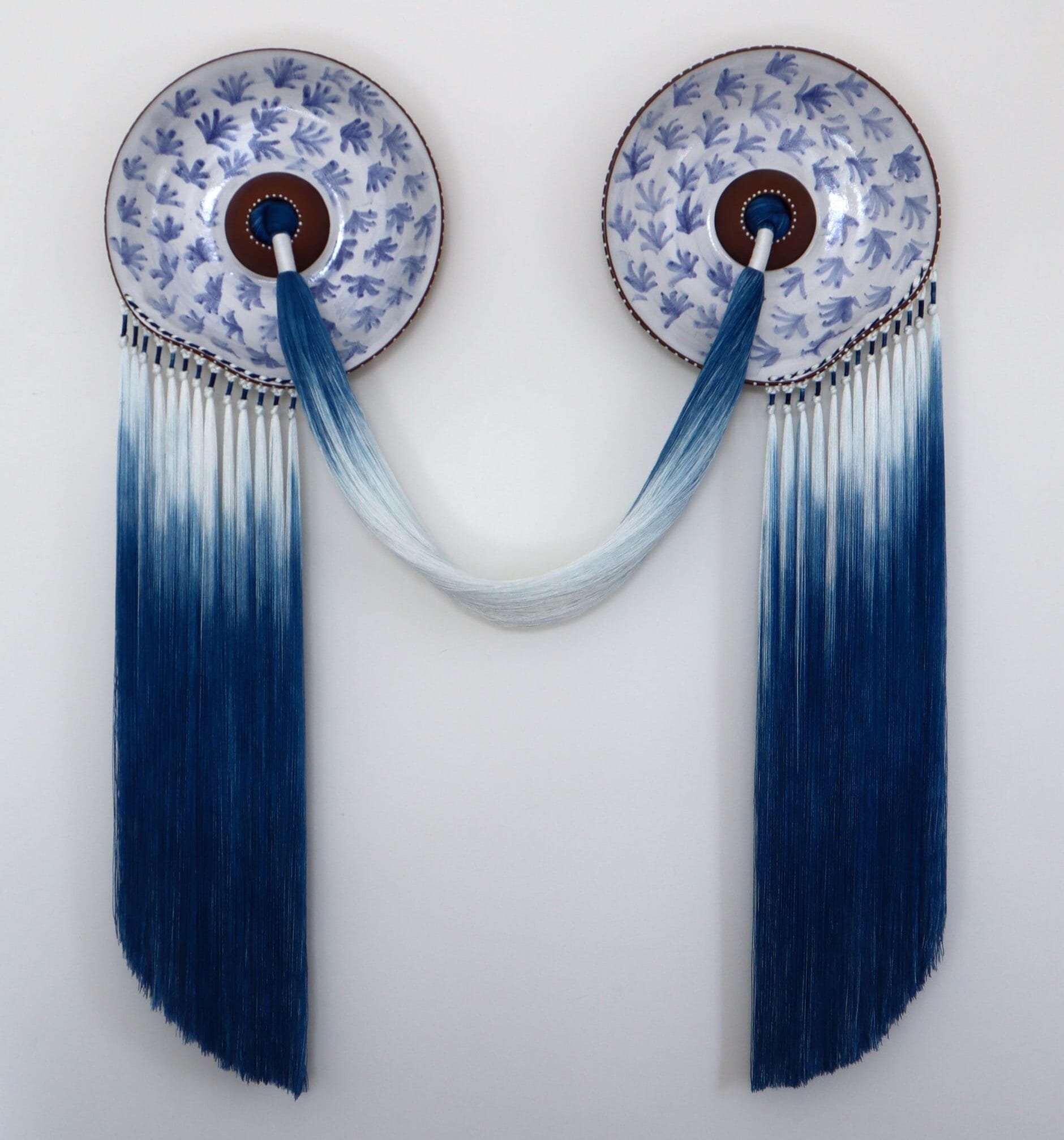 A blue-and-white, ceramic-and-fiber wall artwork by Nicole McLaughlin