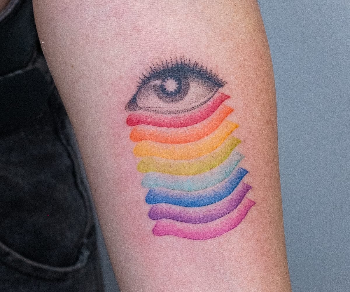 a white arm with a tattoo by Nano Ponto of a vibrant gradient emerging from a black and white eye