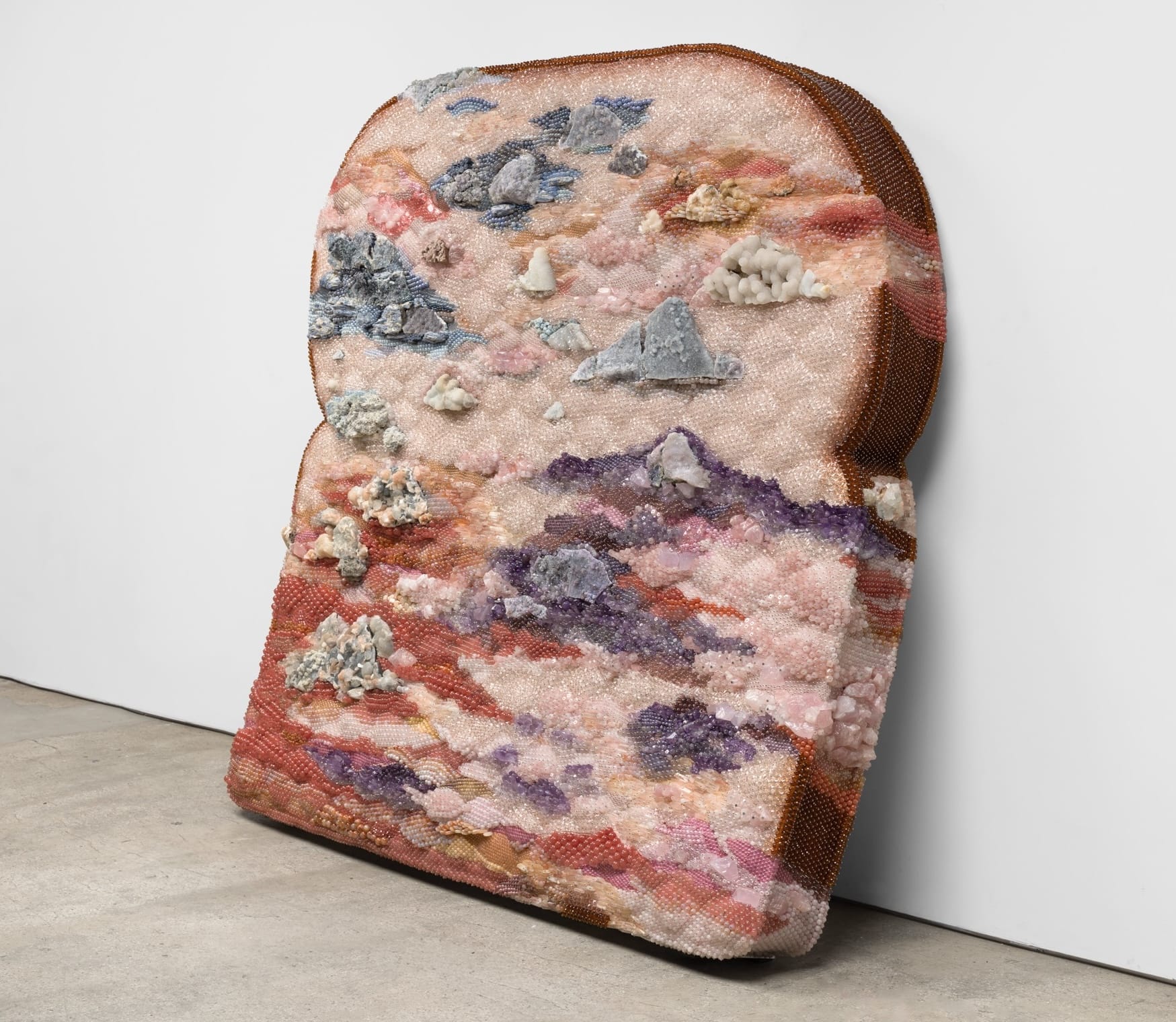 A sculpture of an oversized piece of moldy bread made from beads