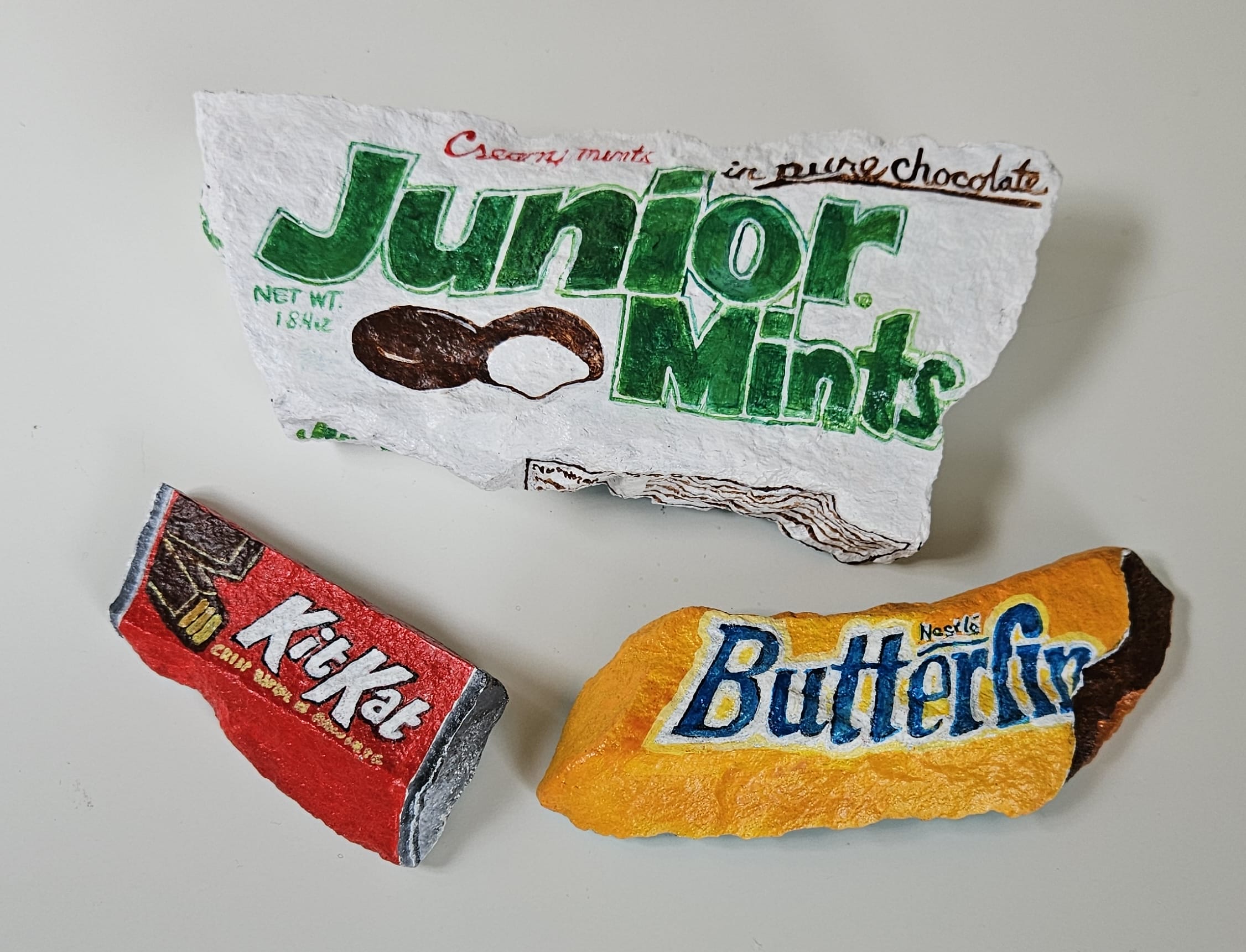 Painted rocks by Elizabeth Saloka that resemble Butterfinger, Kit Kat, and Junior Mints candies