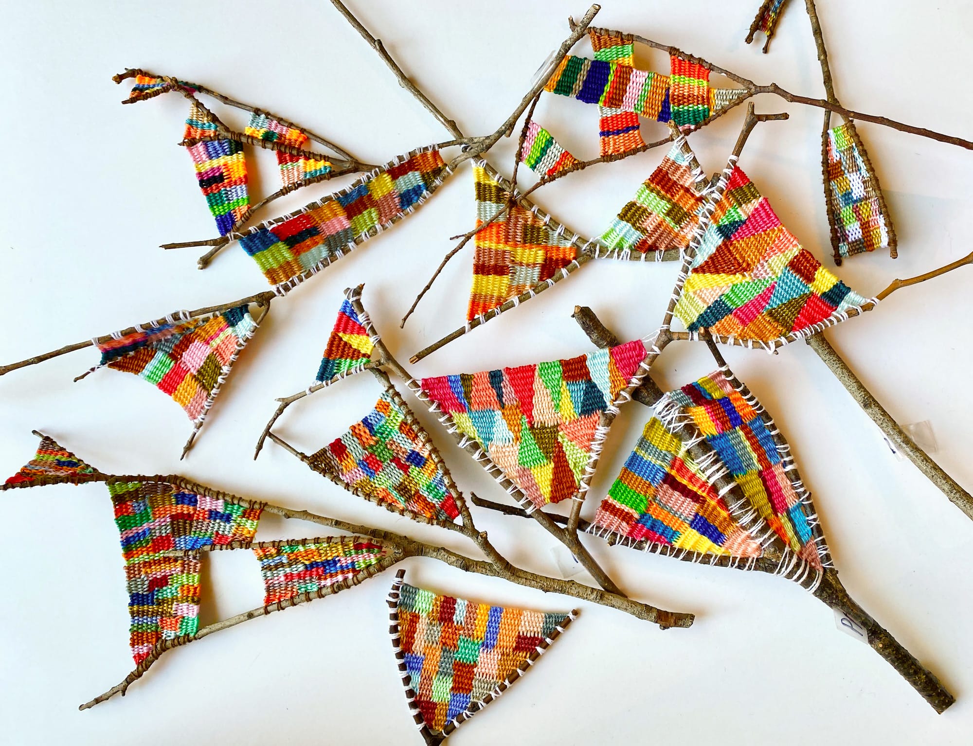 a collection of wish bones with colorful fiber woven between the bones by Kaci Smith