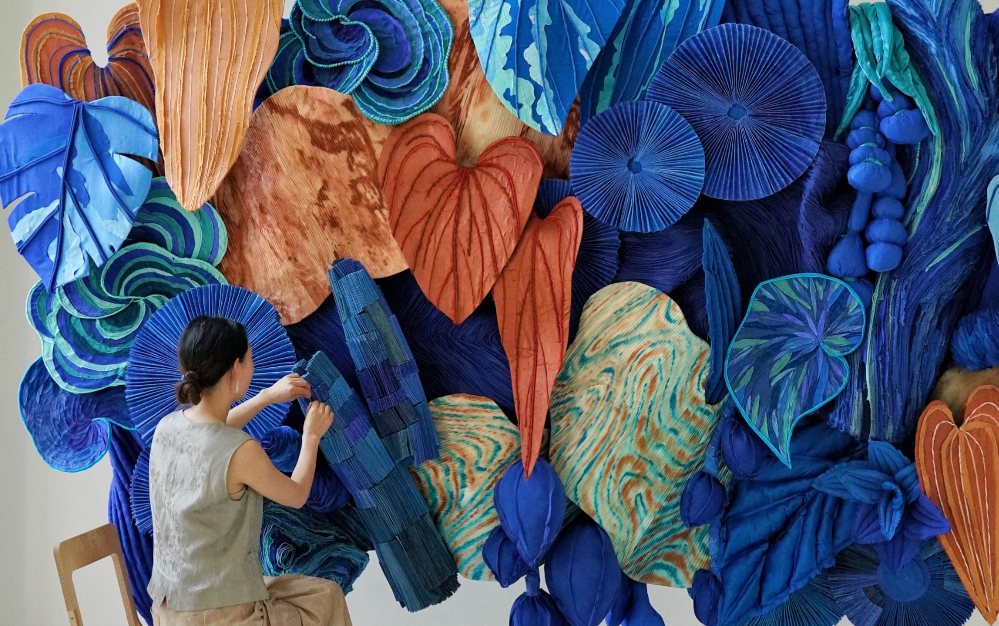 the artist working on a blue and orange botanical installation