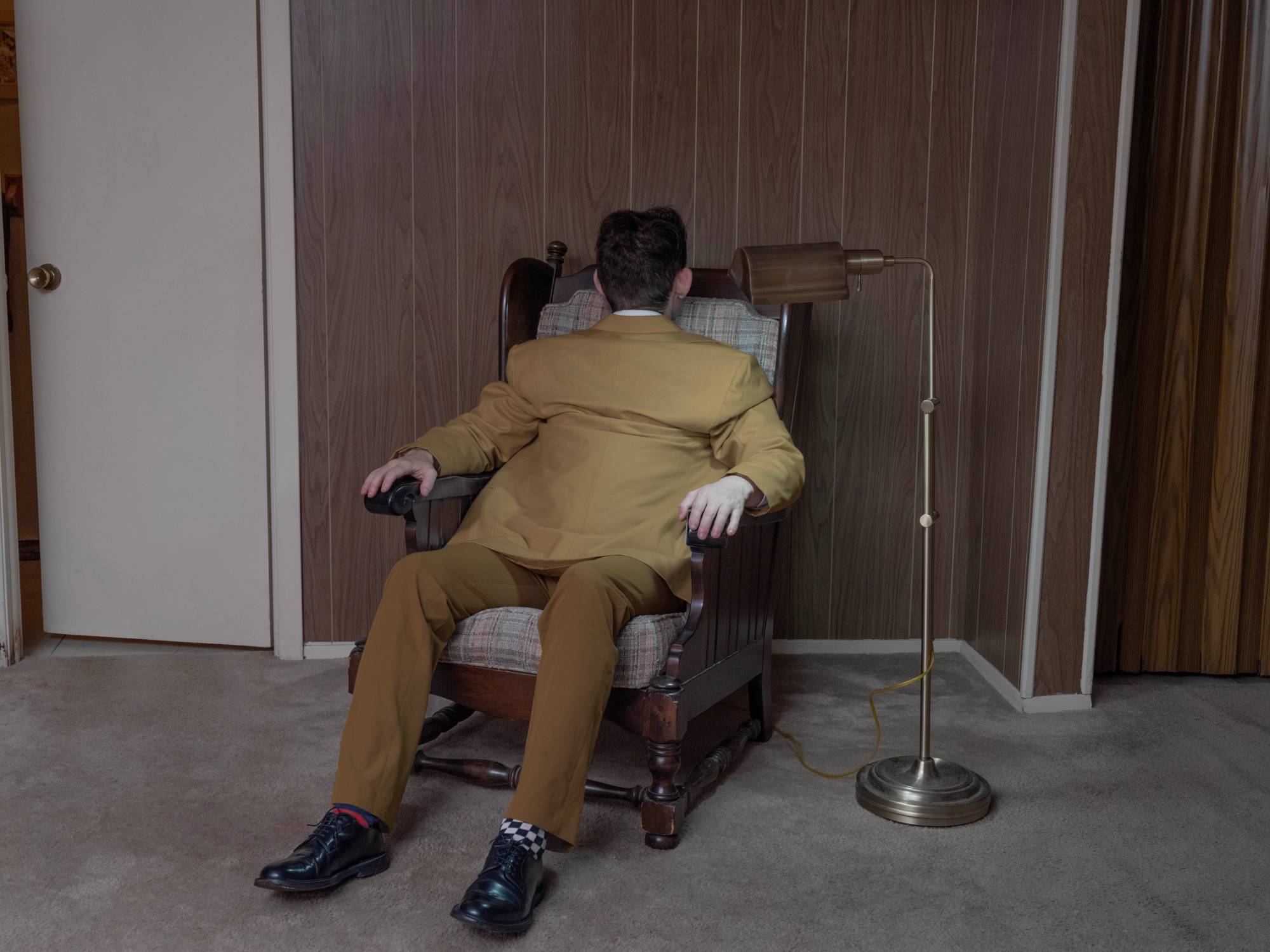 a surreal portrait by photographer Ben Zankn depicting a figure sitting at a seat, its head and back turned the opposite way